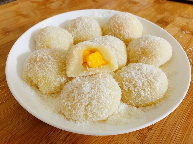 压扁成饼状,放上芒果块,收口捏紧,在椰蓉盘中滚上一圈椰蓉,摆盘即可