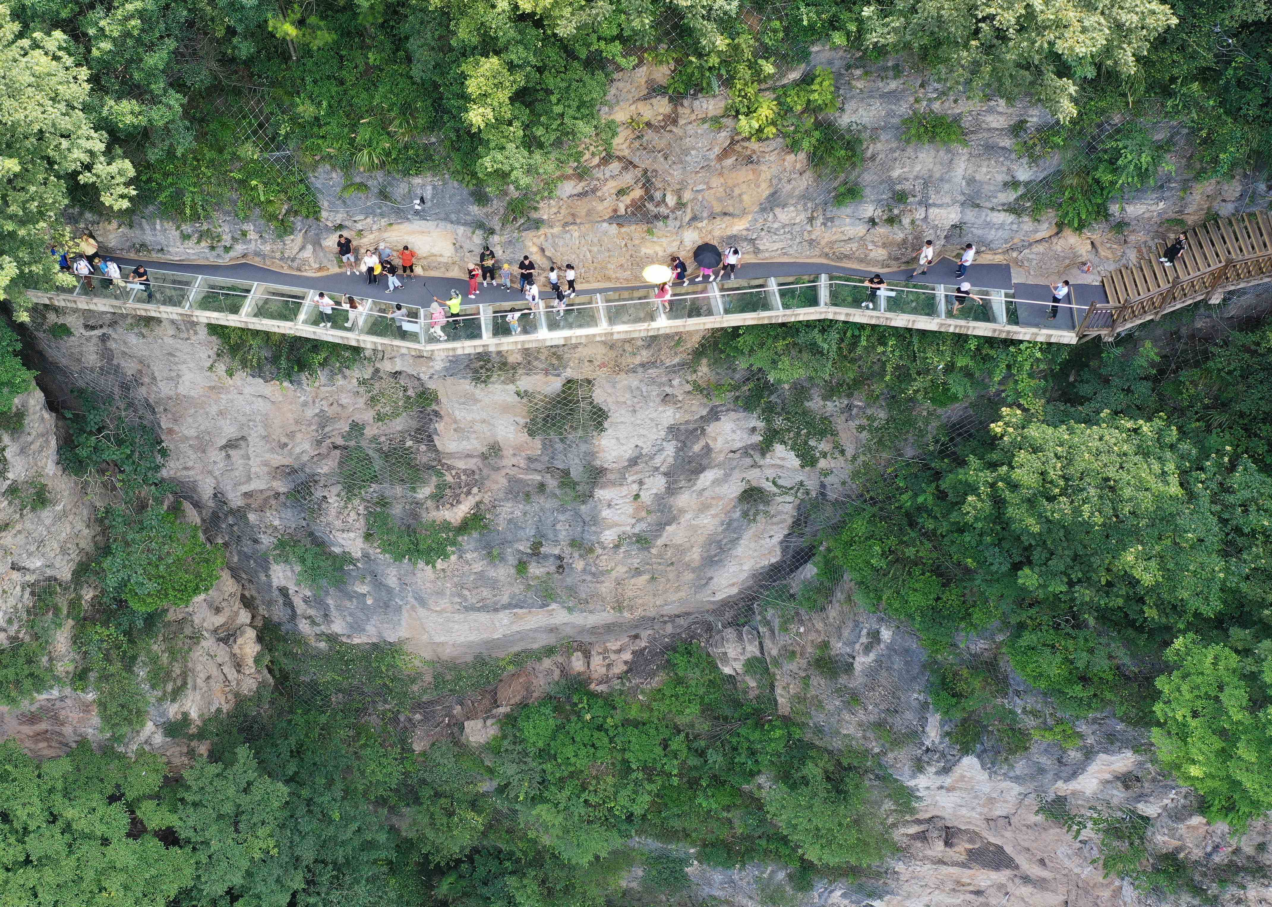 游人在张家界大峡谷景区体验悬崖玻璃栈道游览项目 .