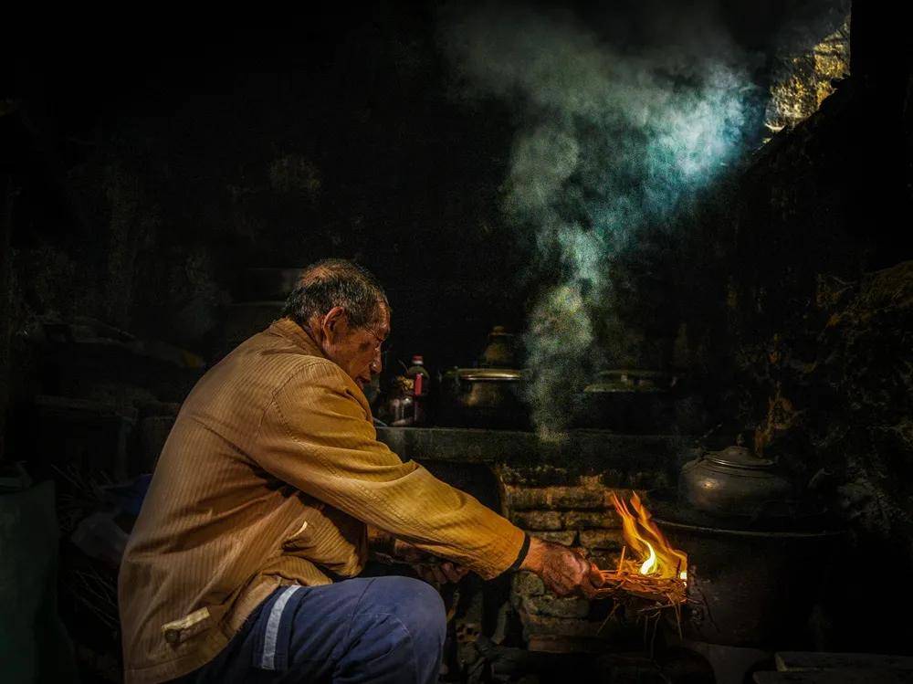 《人间烟火》厨房内,老人正在用柴火烧火做饭,燃起缕缕炊烟.