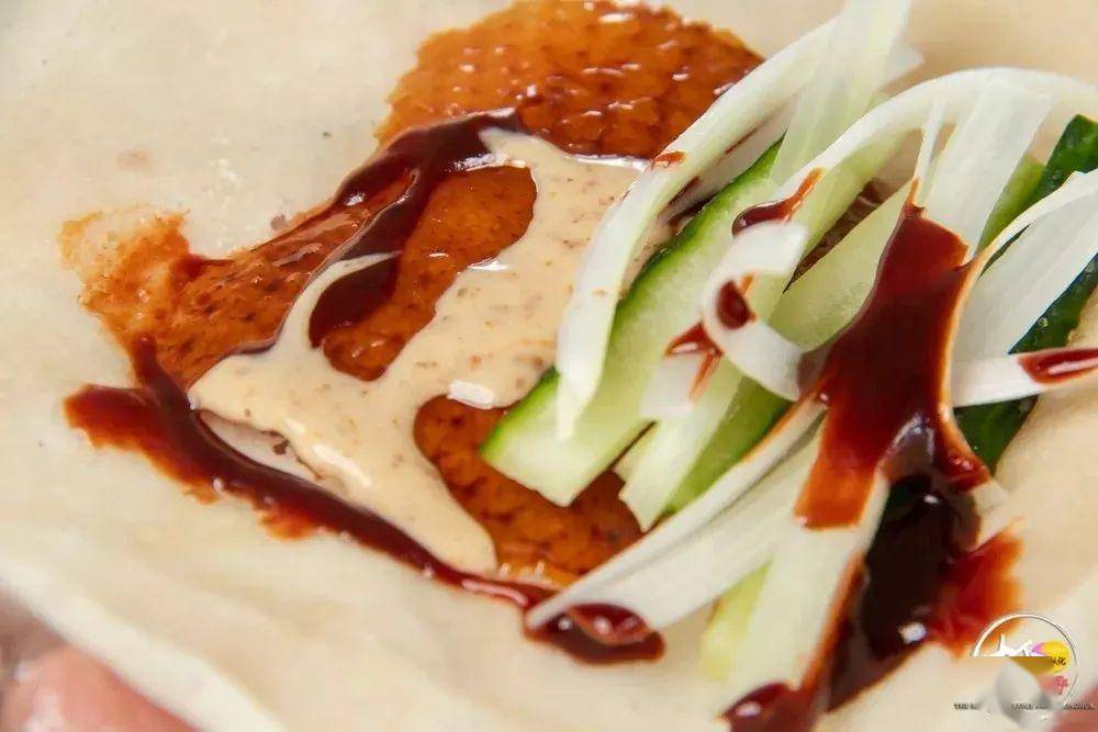 面皮饼一卷而食蘸一点海鲜酱 一点特制芝麻沙拉酱放上一片香脆的烧鸭