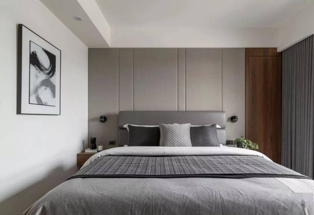 床头背景墙是软包质感,搭配灰色皮艺靠背的床铺,灰色的床单布置