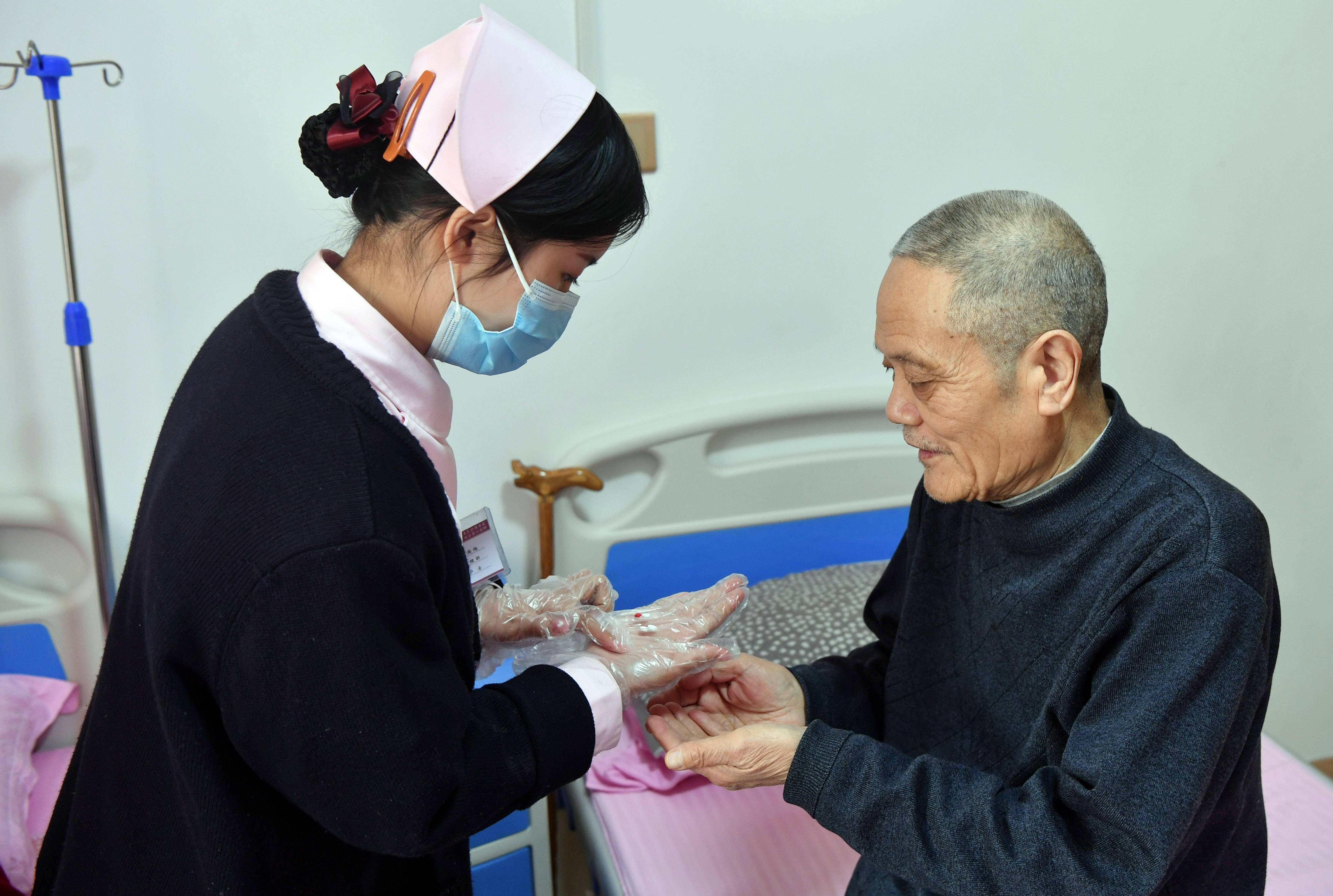 2月8日,在郑州爱睦家护理院,医护人员帮助老人服药.