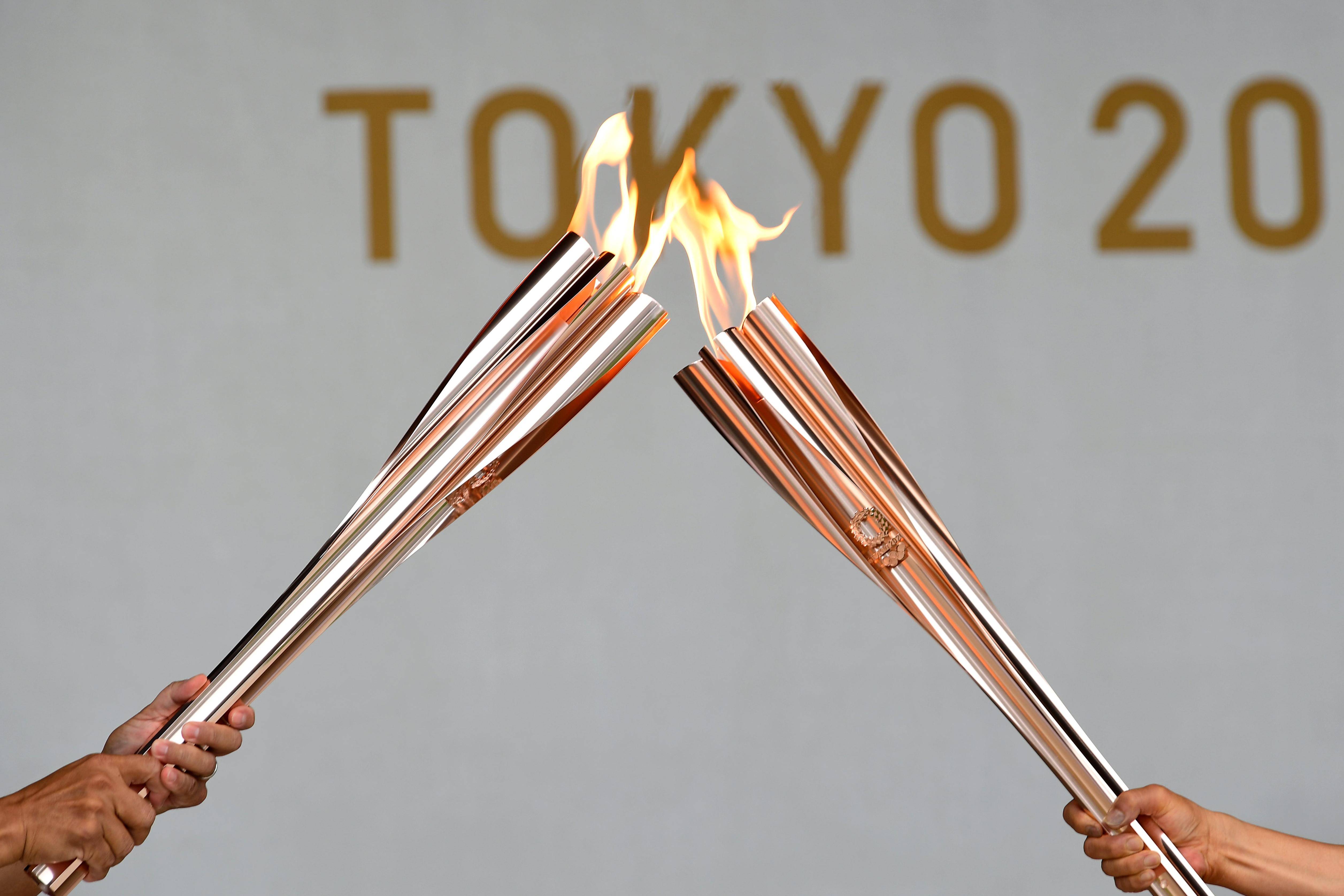新华社照片,东京,2021年7月9日7月9日,两名火炬手进行圣火交接.