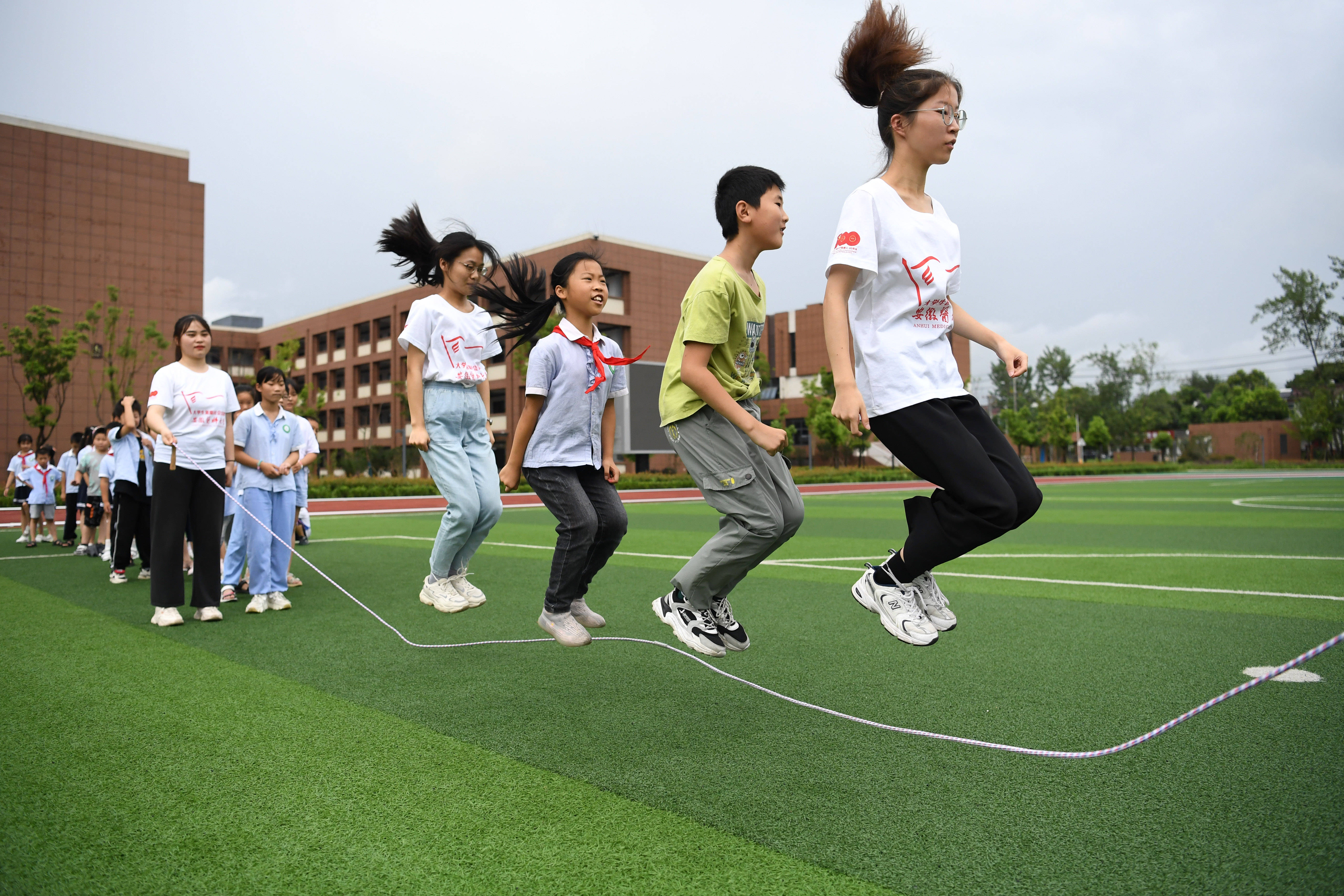 7月17日,大学生志愿者在花岗学区中心学校和孩子们一起开展体育游戏.