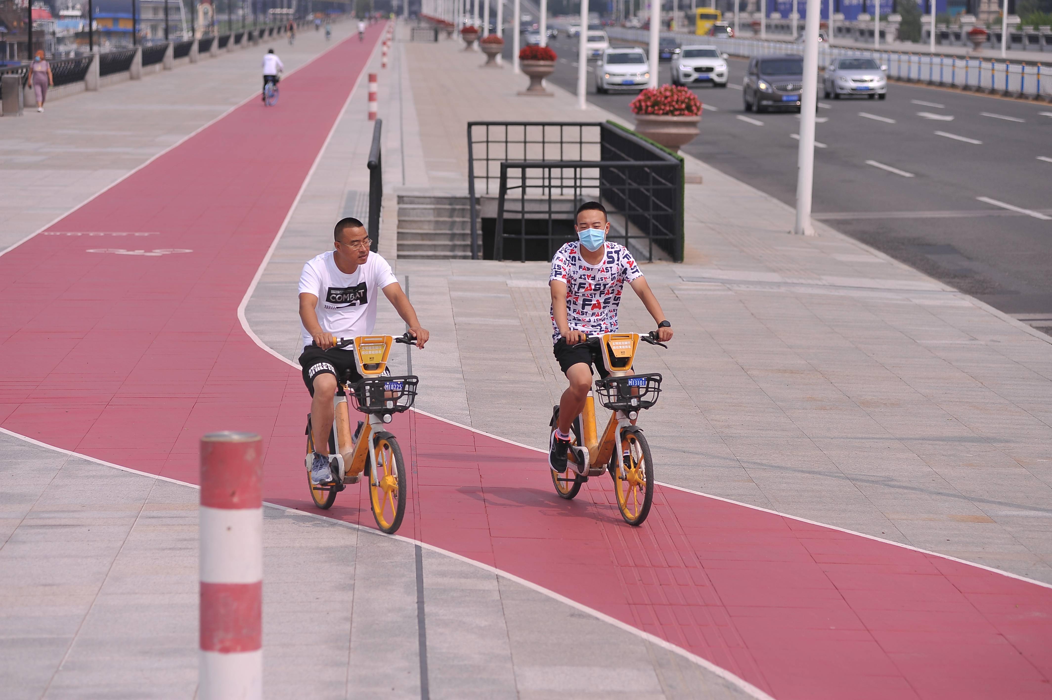 友谊西路人行道上画出自行车专用"红道",市民骑行通过