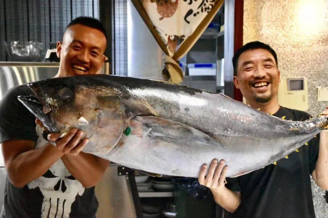 在私房小馆里展示他钓到的狗牙金枪鱼