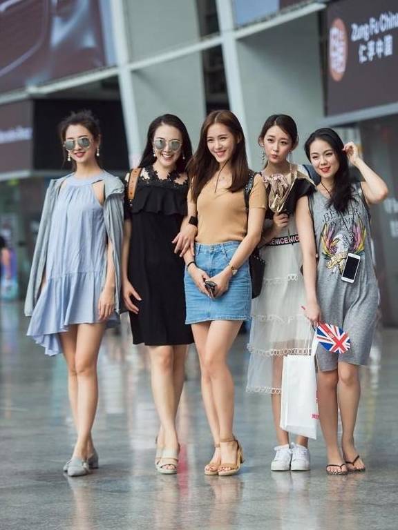 街拍与几个闺蜜夏季里穿着时尚的衣服走在街上美丽动人