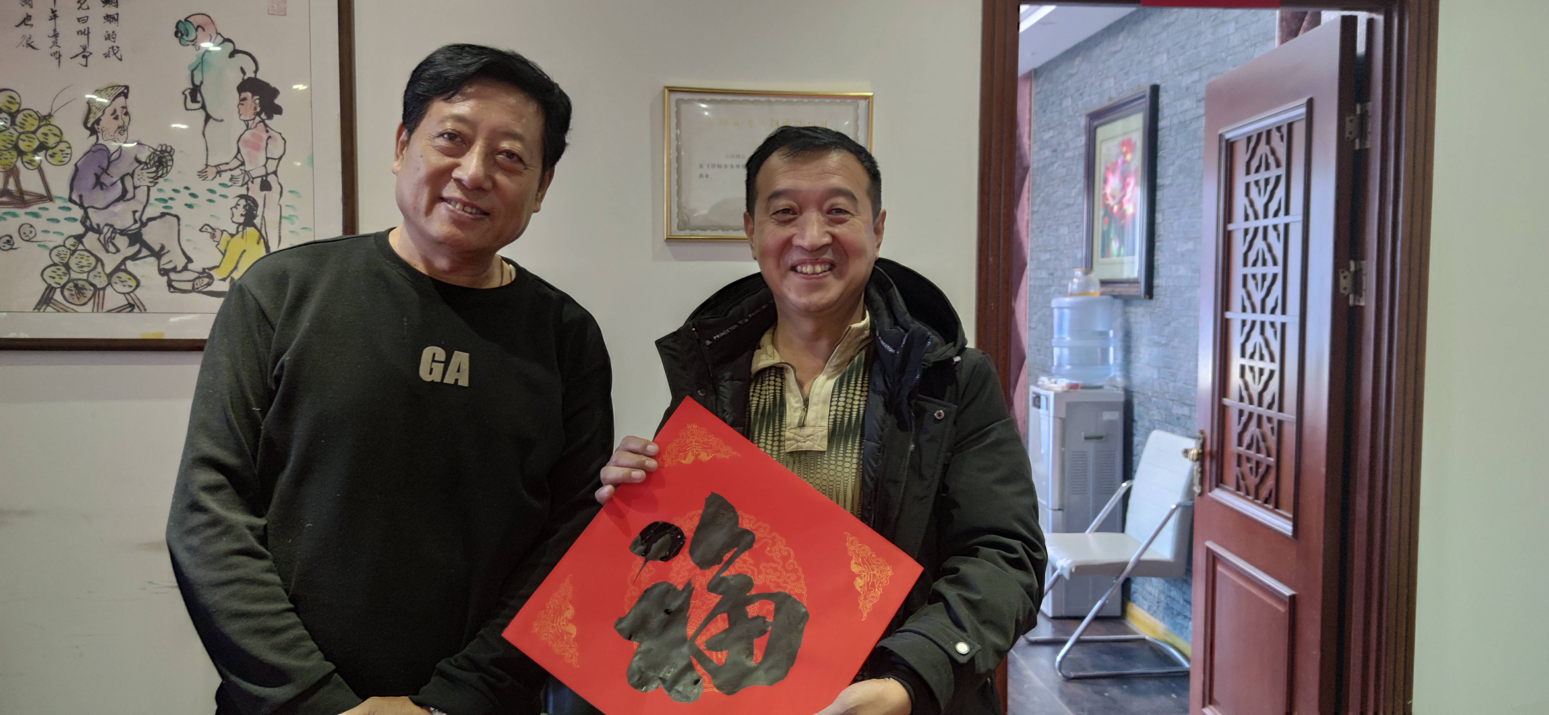 刘建凤老师陈金龙老师和孔广源老师书法家正在专心致志进行写春联活动