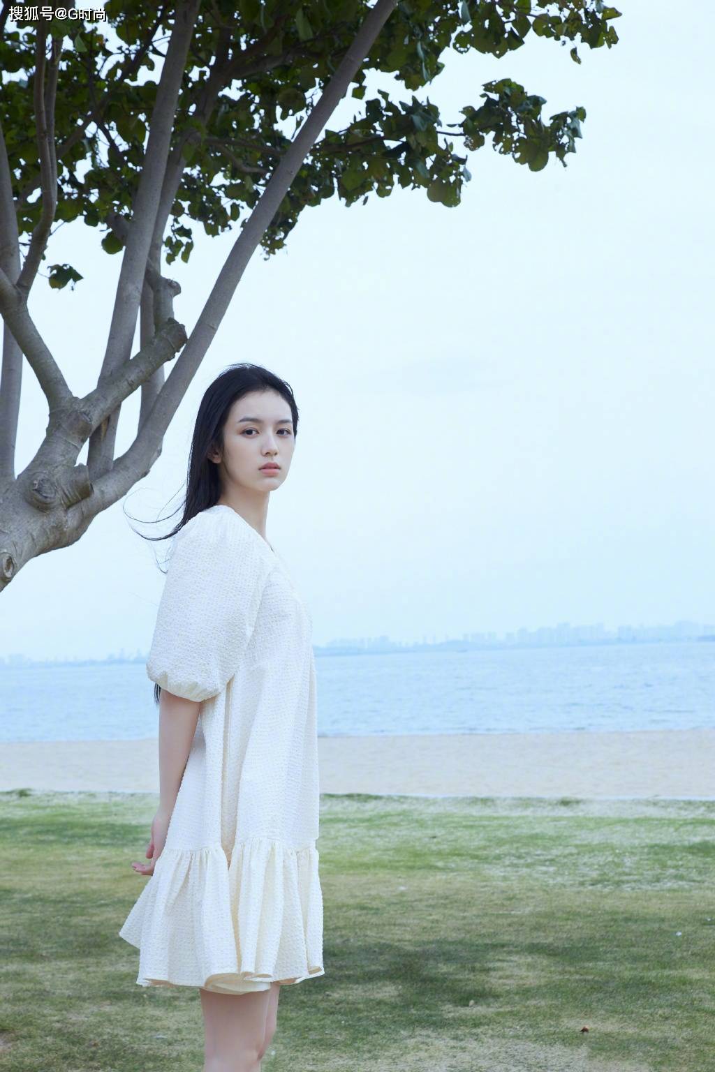 周也身穿白色棉纺连衣裙漫步海边,温柔恬静
