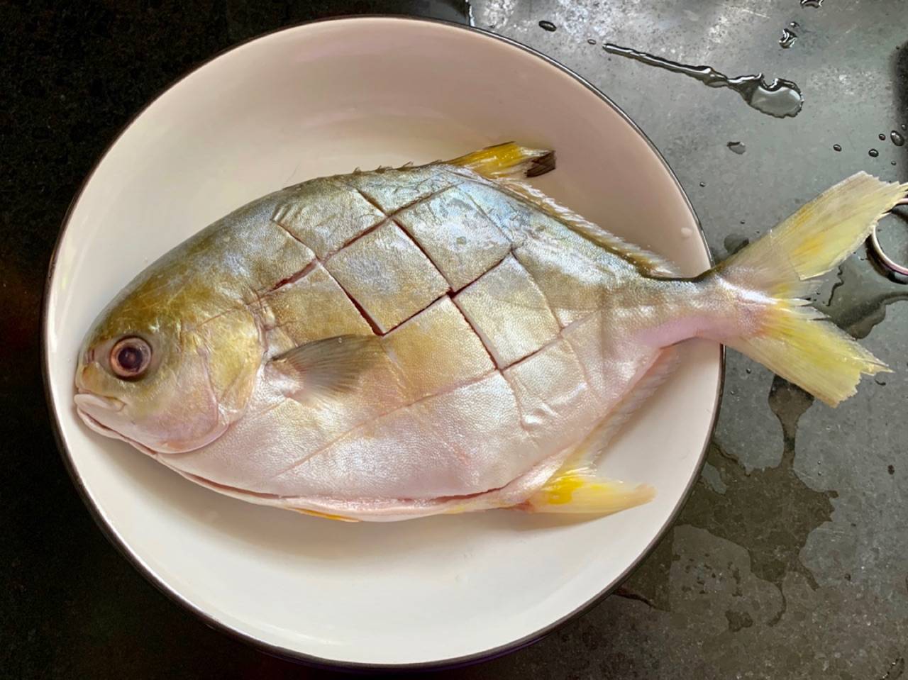 把金鳊鱼的肚子刨开,再把内脏给清洗干净,在金鳊鱼的两面都划上几刀