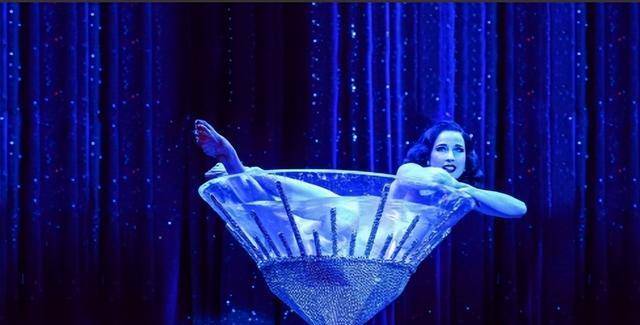 奇的秀展,大红唇的她,脚穿舞鞋,身着水晶礼裙站在巨大的水晶酒杯之中