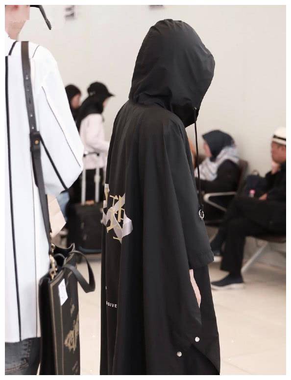 周震南身穿黑色斗篷上衣,背面印有银色图案,头戴衣服帽子,很帅.