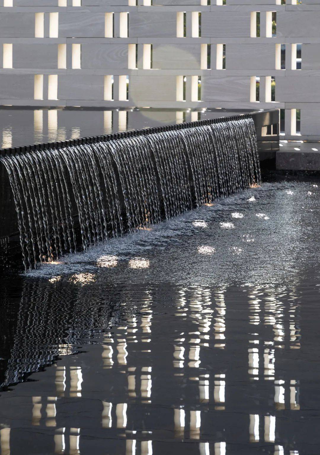 再转折过来是一处精致的镜面跌水,香槟金色的金属logo映衬着素白色的