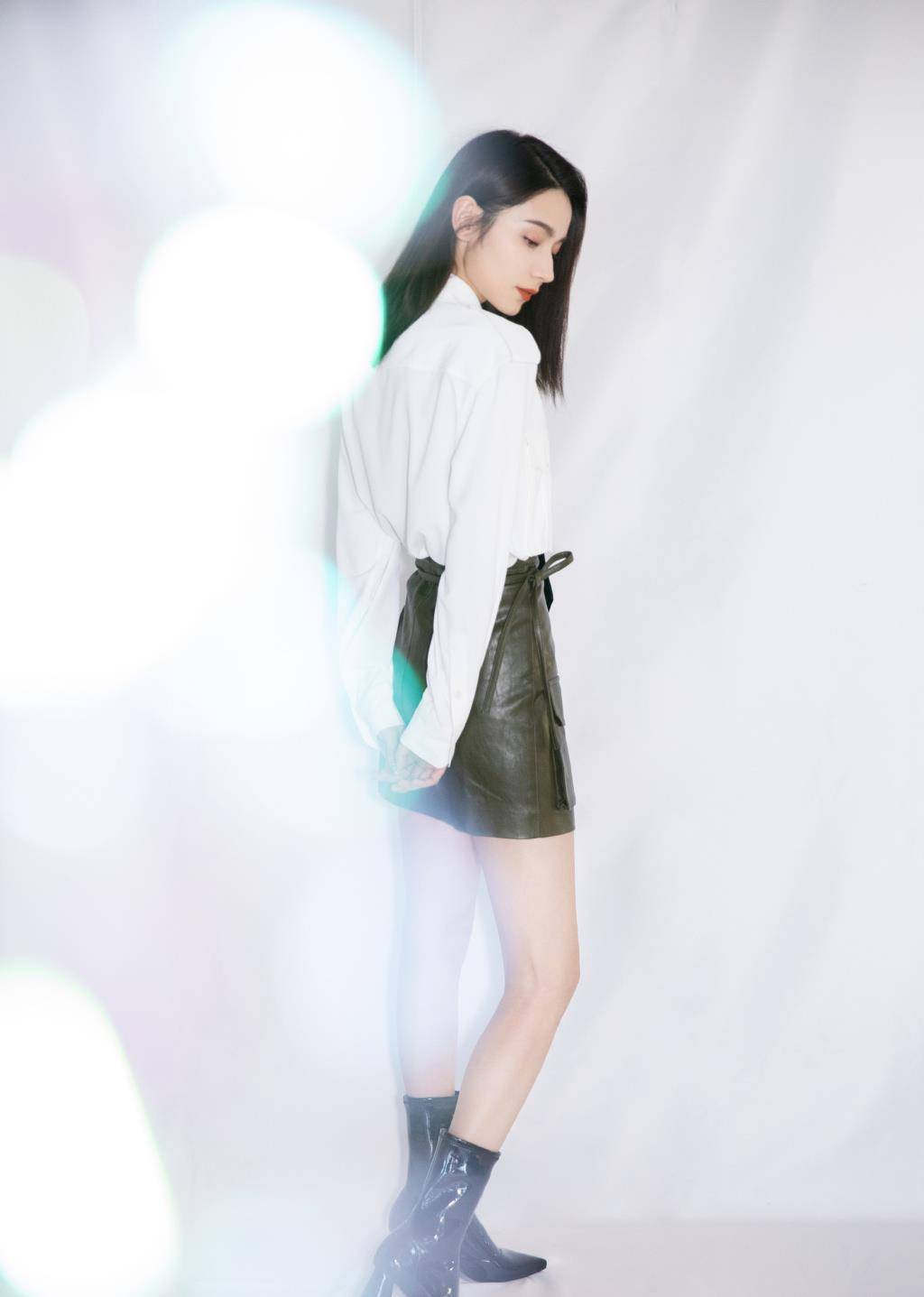 代斯上身穿白色衬衫,系上黑色波点领带,搭配暗红色半身皮质短裙,直接