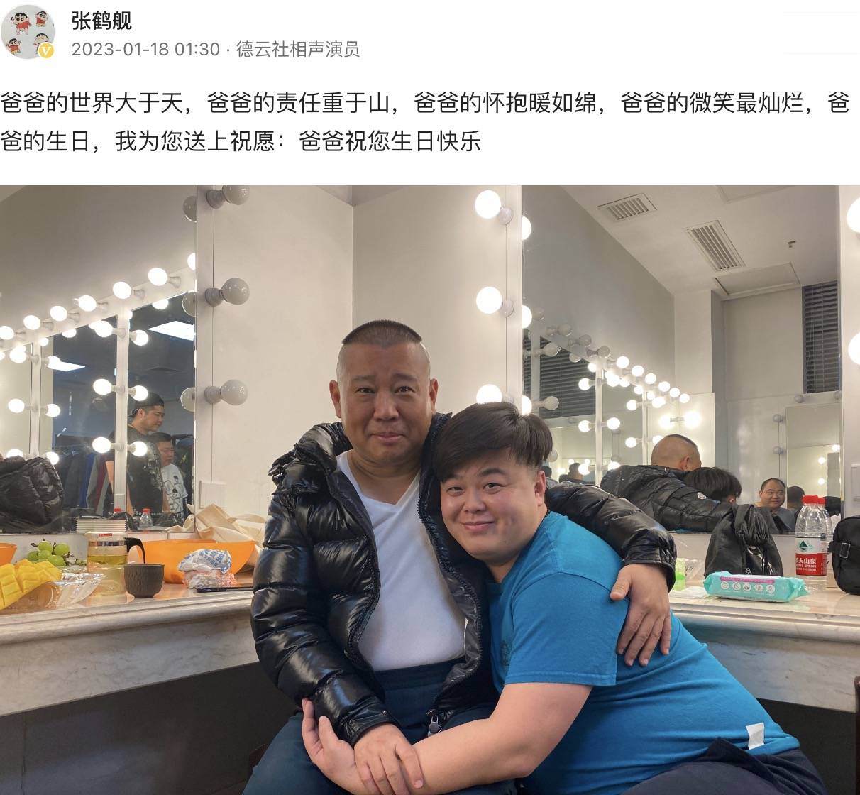 照片中,郭德纲坐在后台化妆间的板凳上,而张鹤舰则是蹲着抱着师父