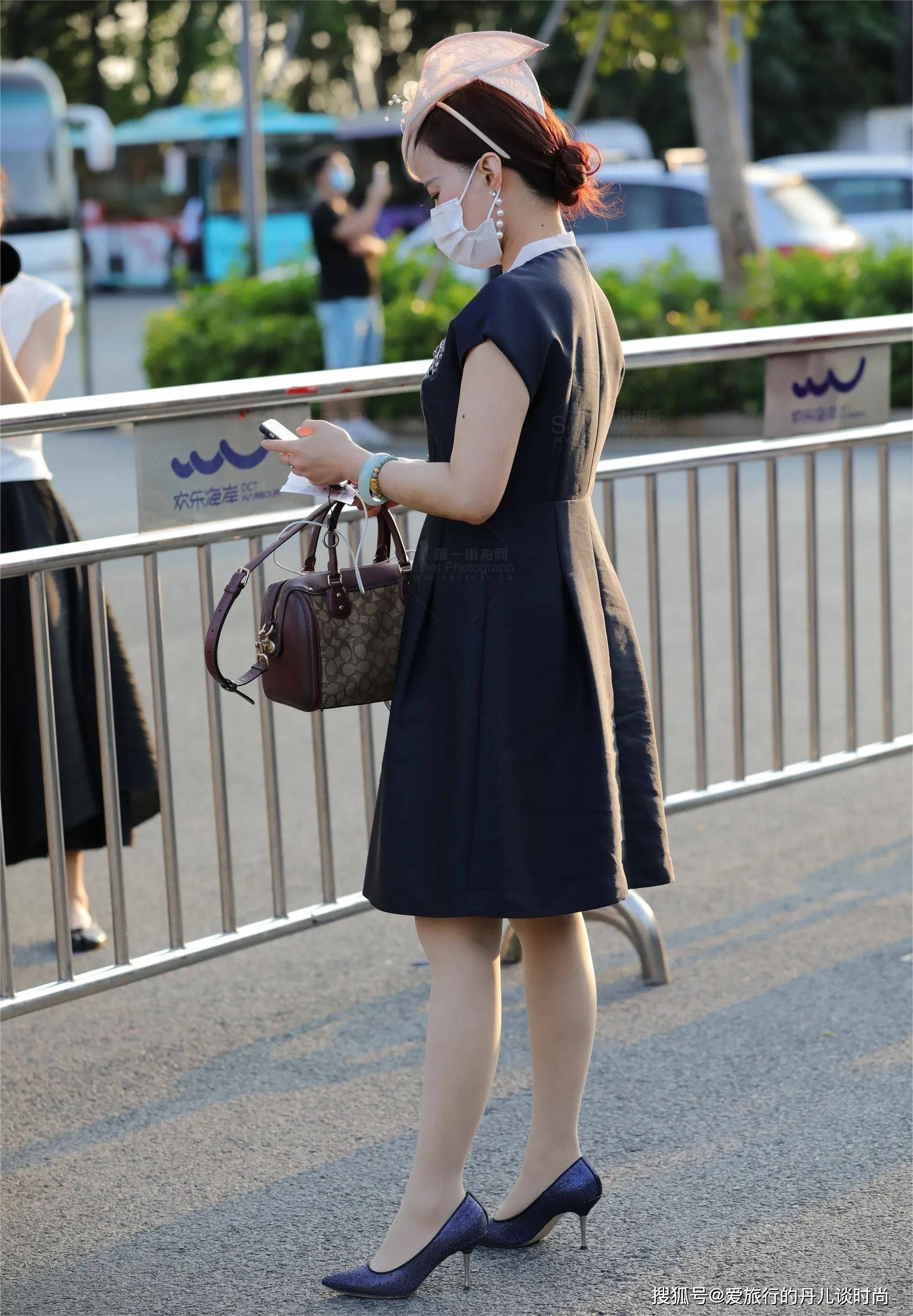 美女一身贵妇打扮,身穿黑色v领收腰连衣裙,手拎紫色手袋很高贵_领口