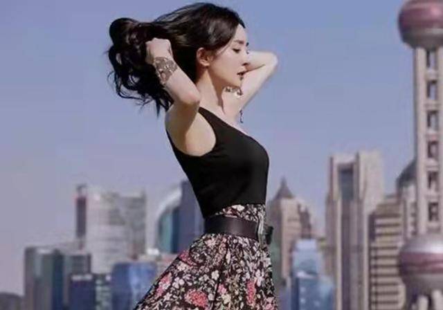 杨幂站在屋顶上,侧身朝图,做了一个双手撩头发的姿势.