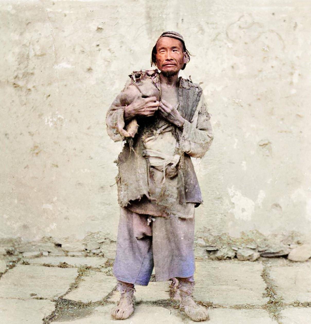 一位老人老人手里捧着水罐,身上的衣服鹑衣百结,因为卫生条件差,还害