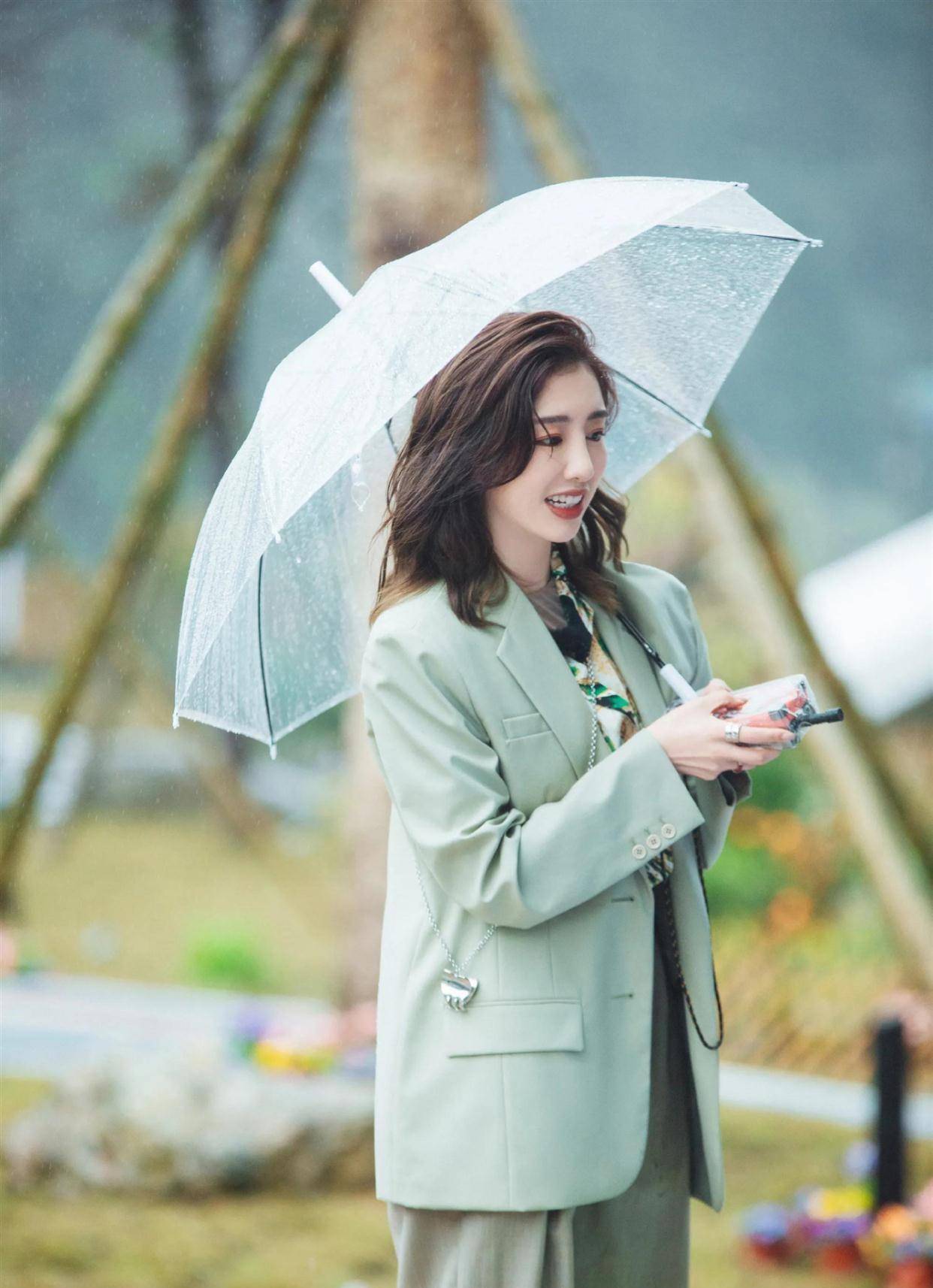 周捷光着脚走在海滩中,无袖的连衣裙更加突出胳膊的纤细感