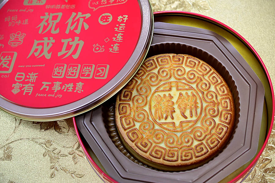 饼中间是繁体的汉饼二字,字体古朴,代表着月饼文化源远流长,四周云纹