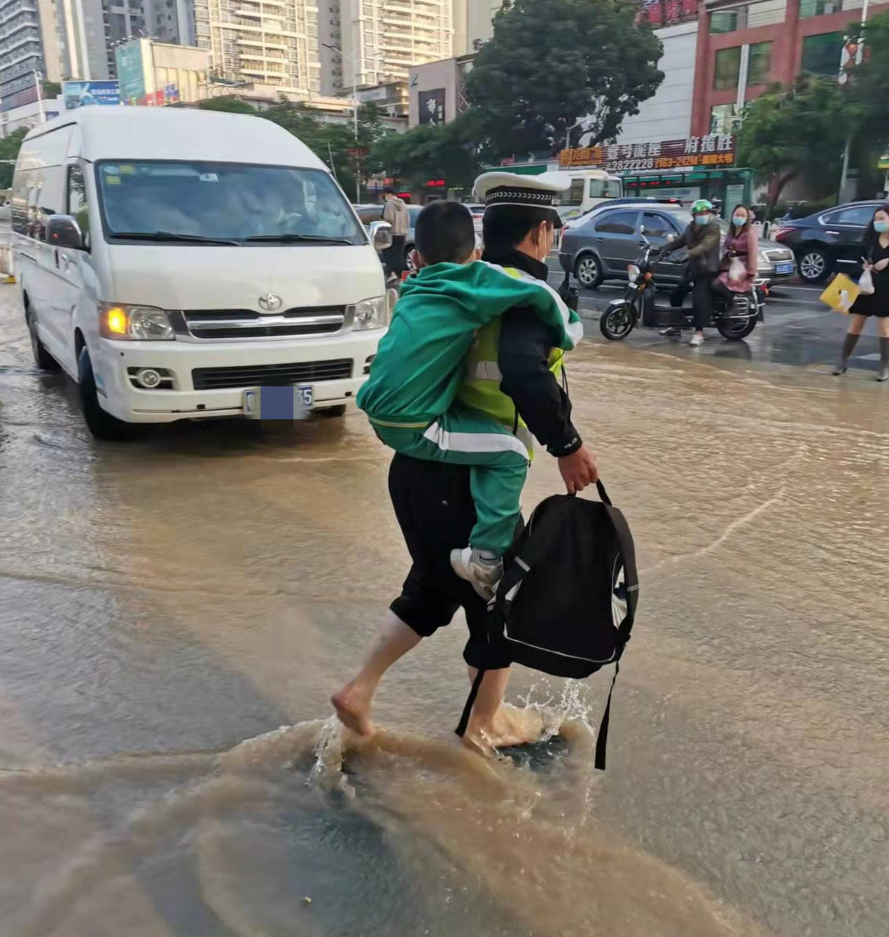 地下水管突发爆裂 交警背学生蹚水过马路_路面