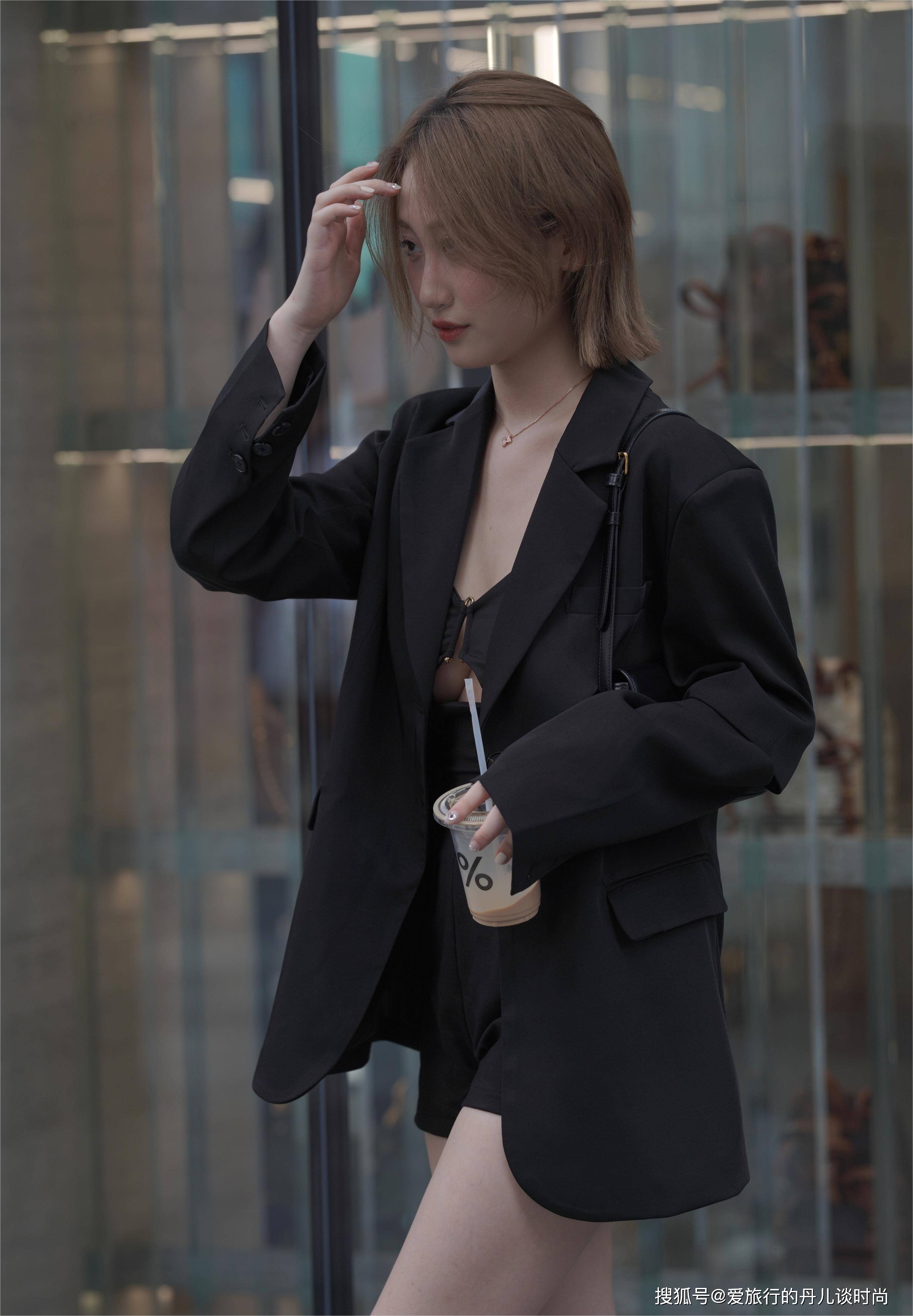 小姐姐身穿黑色长款西服内搭黑色吊带和黑色短裤,西服后背拼接设计