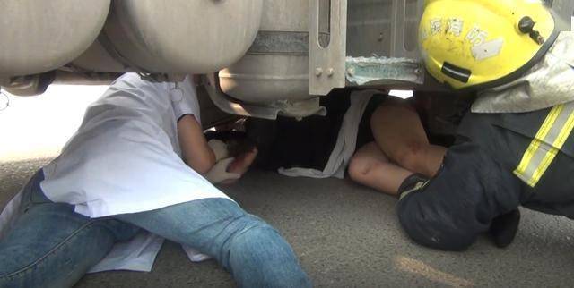 惊险!女子骑车不慎被半挂车卷入车底 消防员钻入车底紧急救援