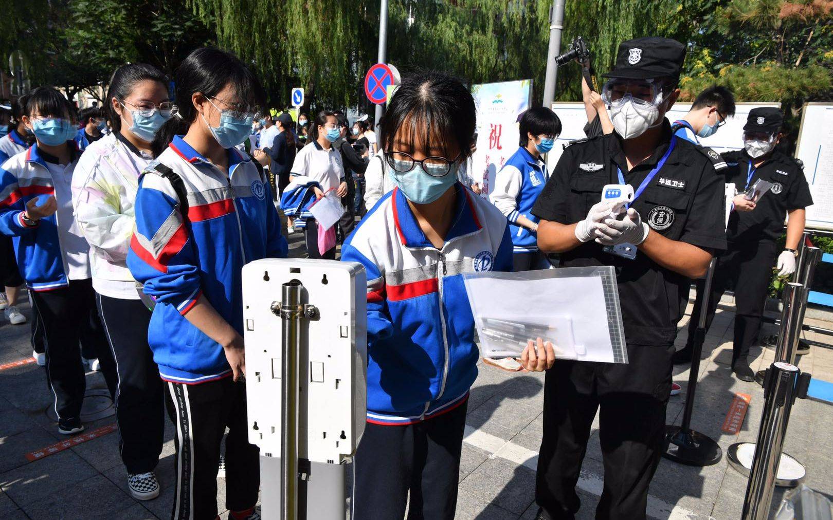 上午8点20分,考生开始进场,检测人员为学生丈量体温,并提示考生用入口