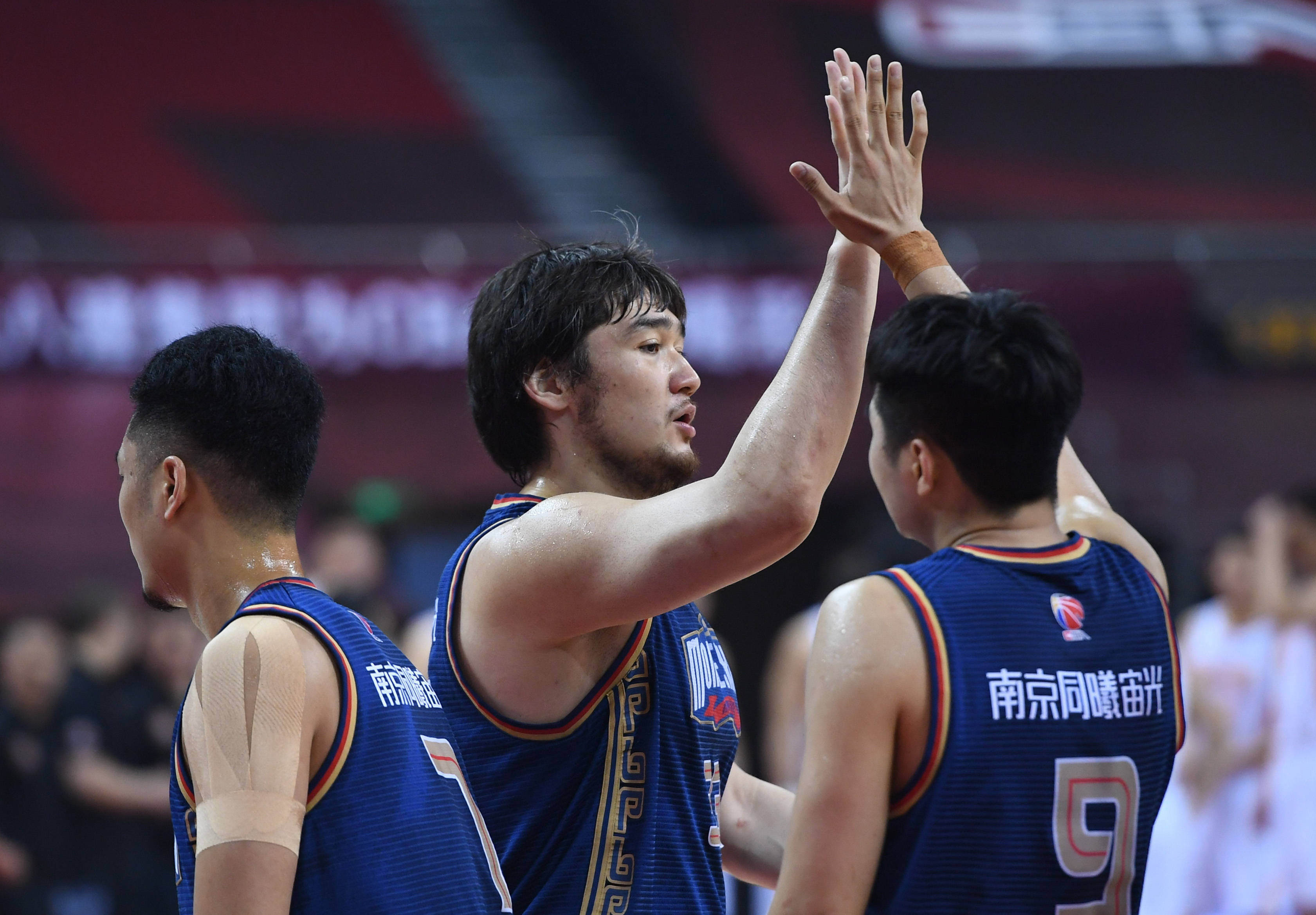 7月15日,南京同曦宙光队球员买尔丹(中)在比赛中和队友乔文瀚(右)击掌