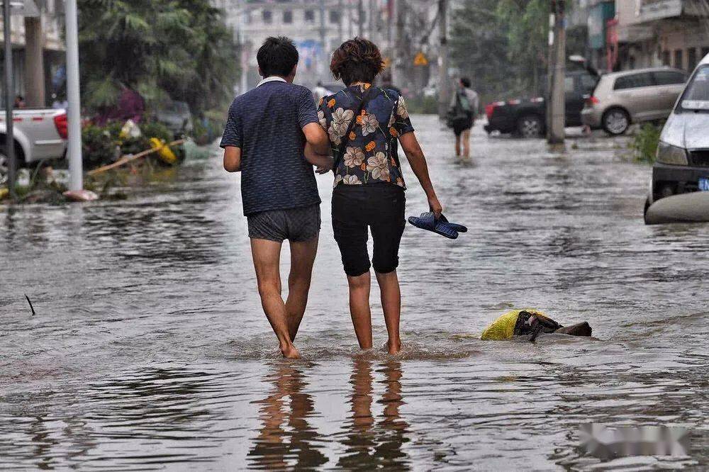 7月22日早6时,一对夫妻趟着水相互搀扶着返回家中