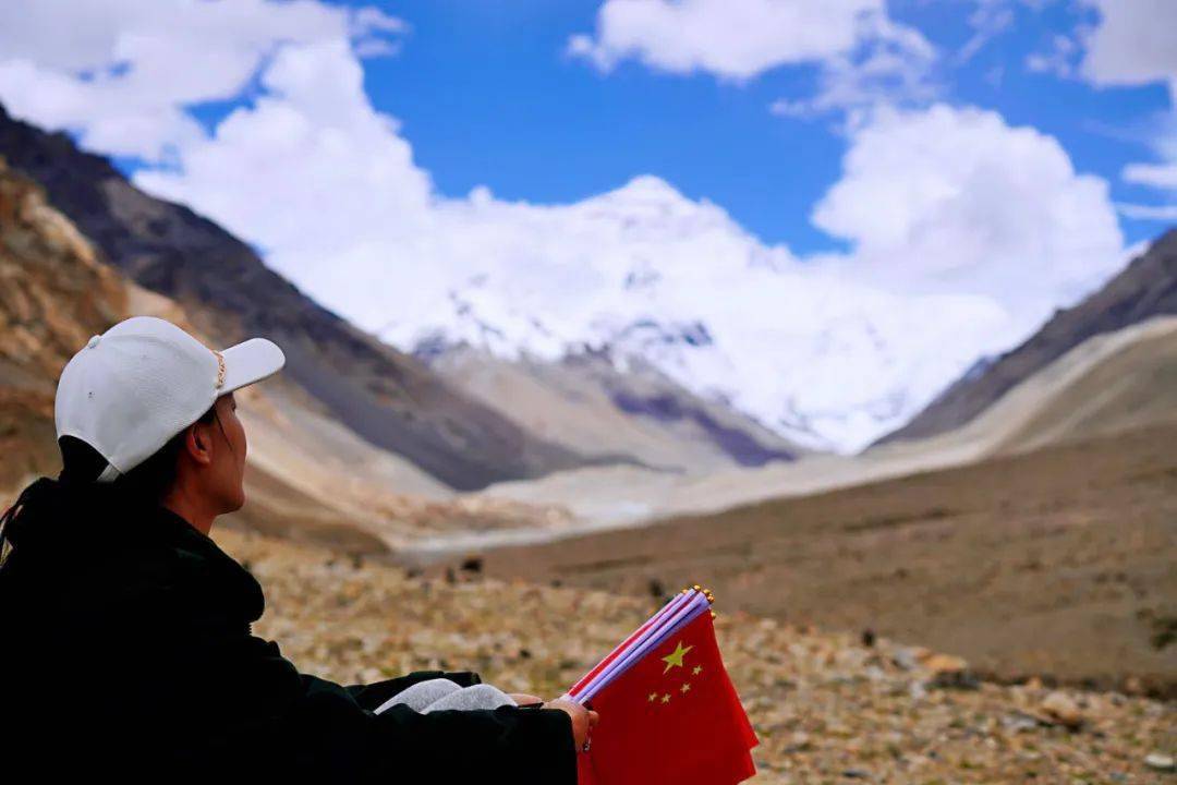 图为:王蕾蕾拿着国旗双手抱膝坐在画面一角(小编:看着她的背影感觉挺