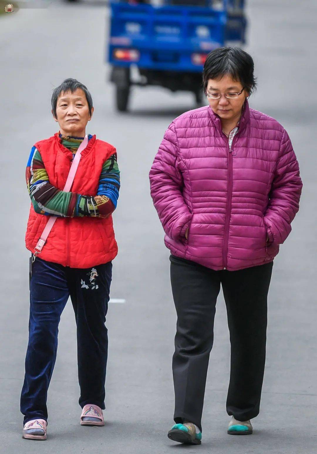 走在路上的两位市民把手放在衣袖和口袋里取暖.