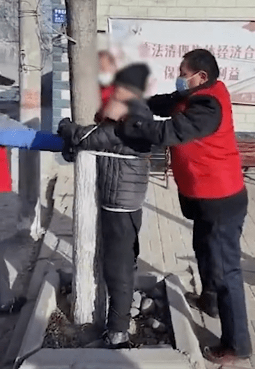 近日,河北石家庄藁城区 一段老人外出 被身穿红马甲的人 绑在树上的