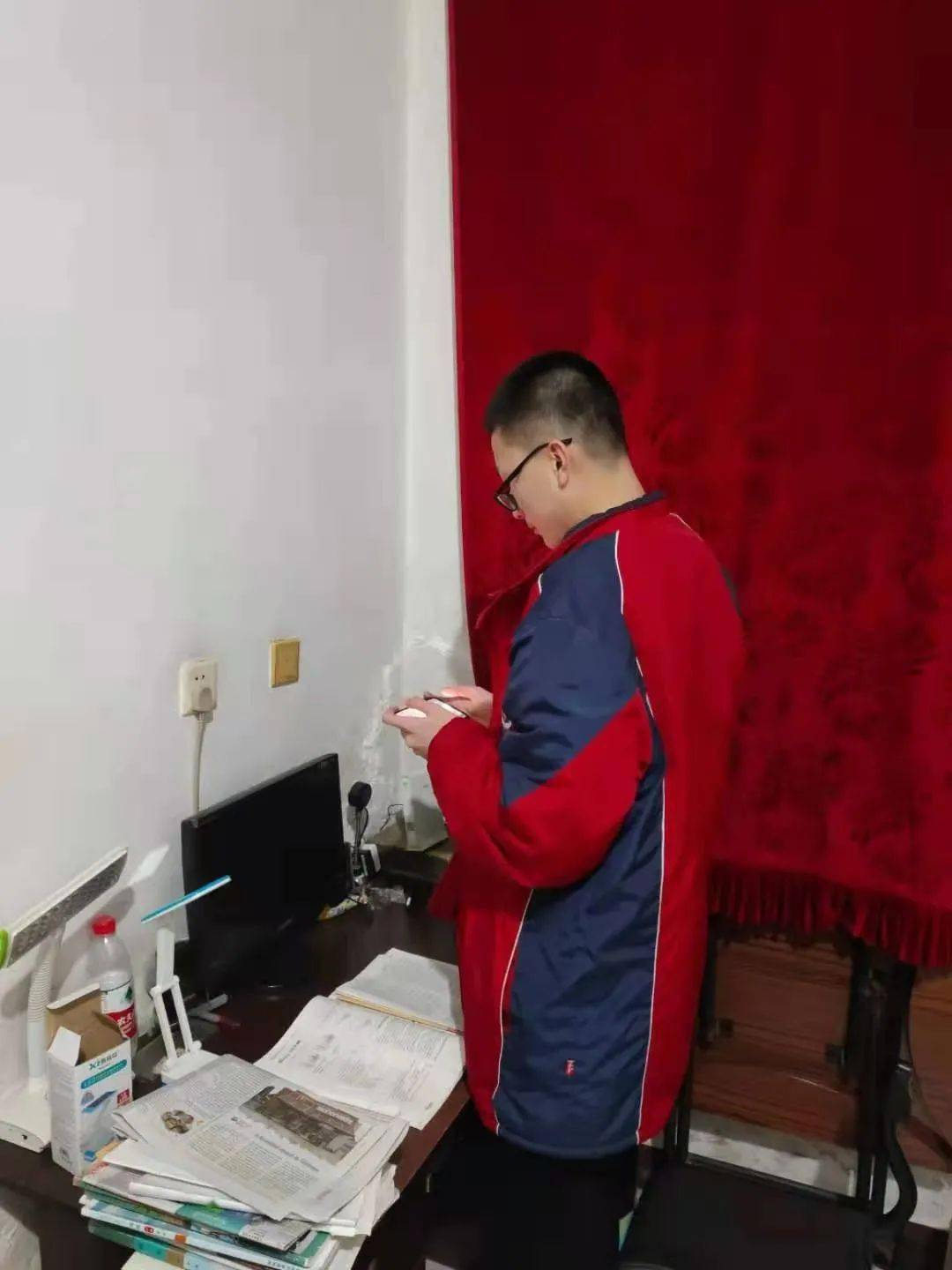 高一高二年级同学在移动设备的另一端穿校服,唱国歌.