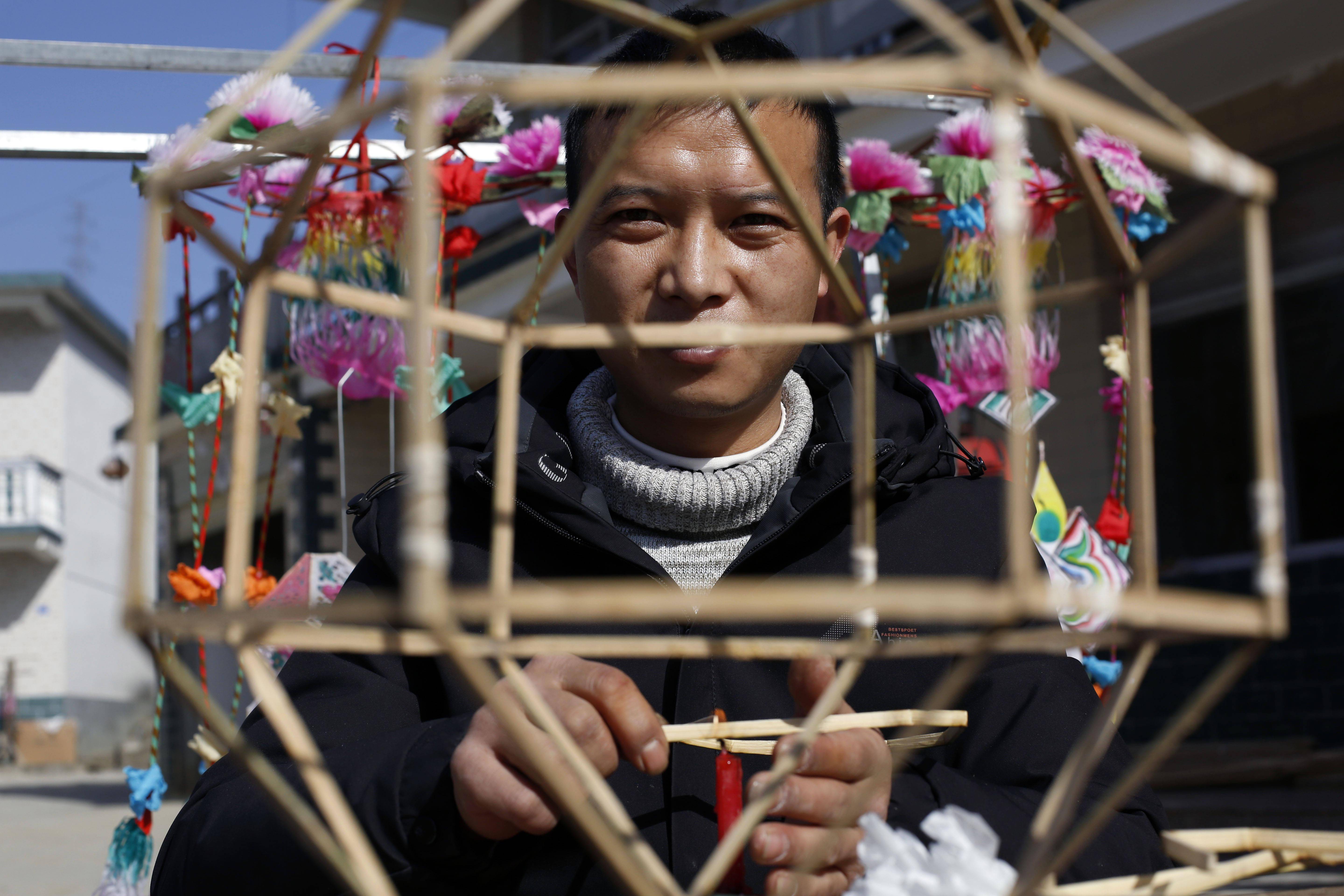 储南赞在扎灯笼.用蜡烛火烘烤竹篾.半小时后,一个灯笼模型便做好了.
