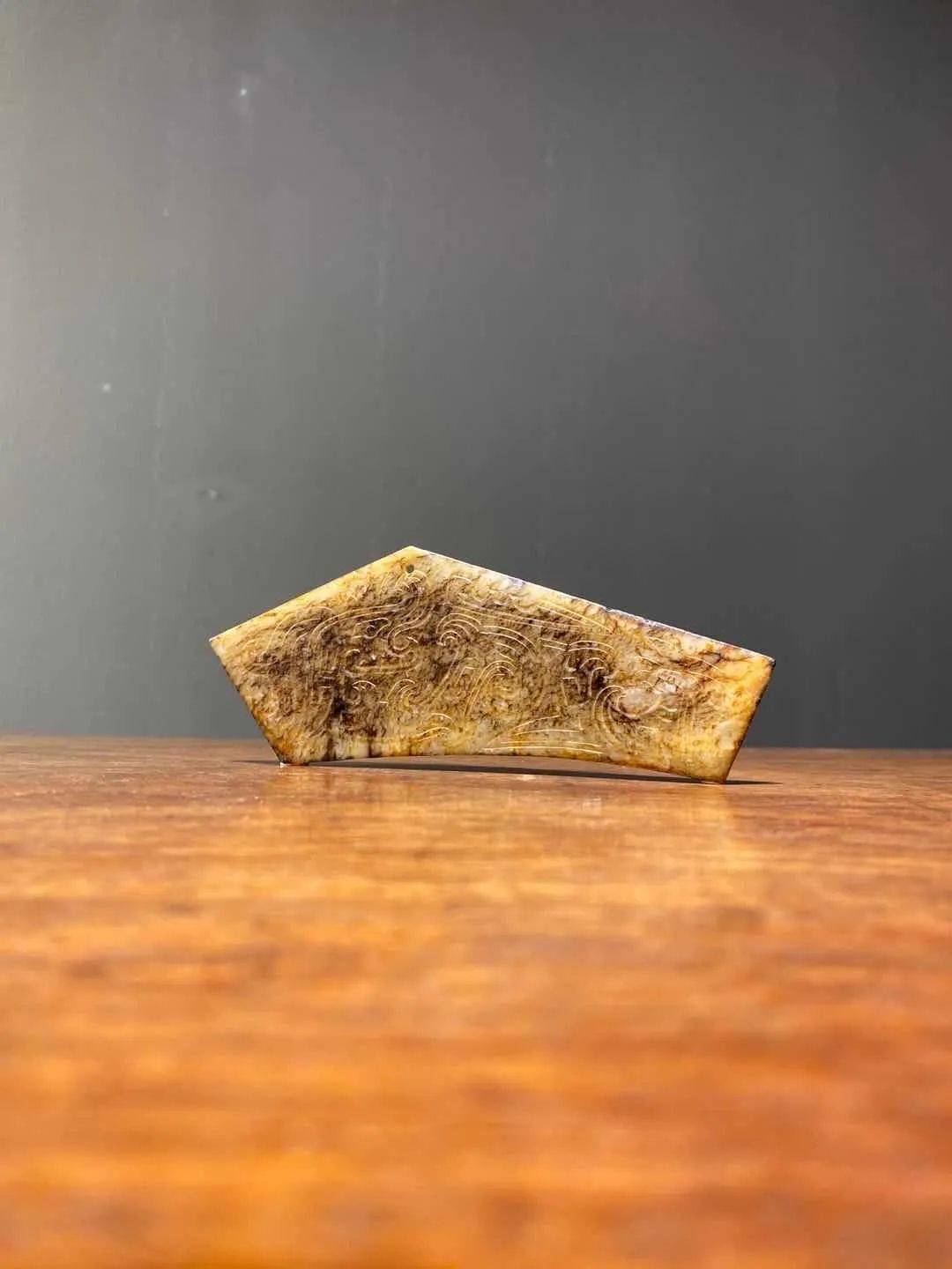 古代祭祀时打击乐器磬,以质地细腻油润的新疆和田褐沁斑白玉雕刻而成