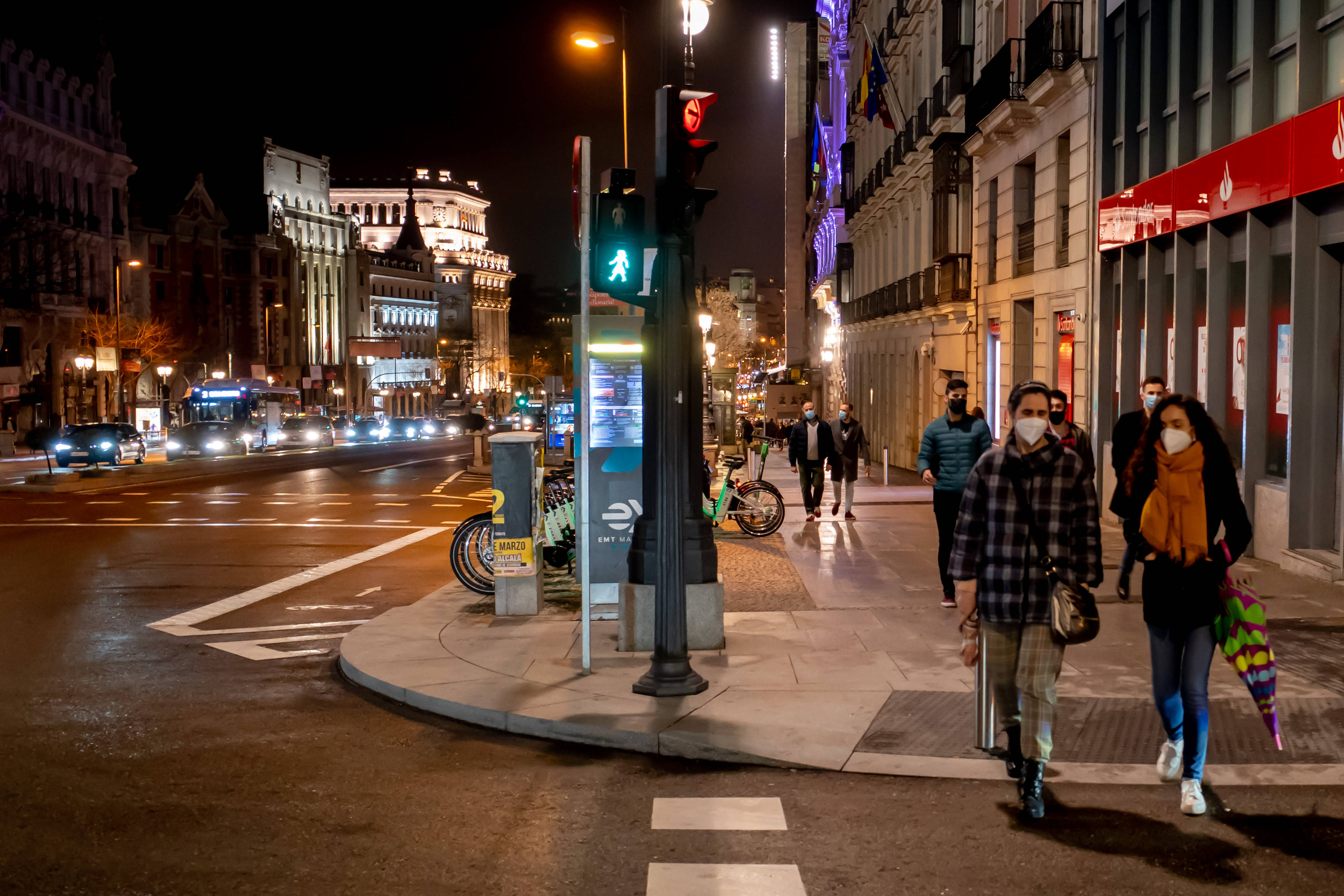 3月7日,人们在西班牙马德里街头的行人信号灯旁过马路