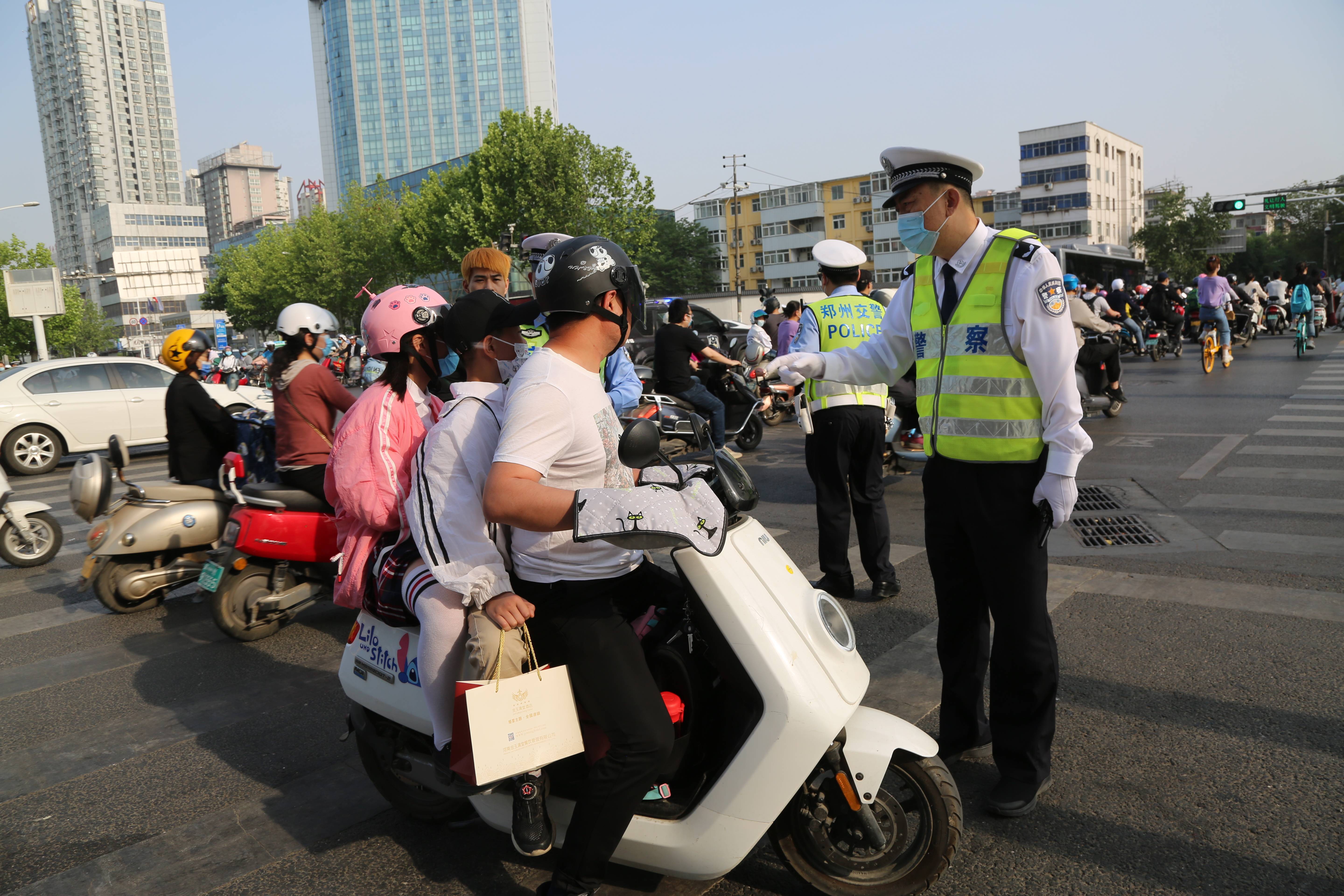 街头骑电动车戴头盔已成主流但不规范佩戴仍存在安全隐患