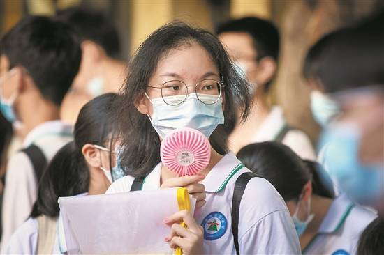 天气很热,父亲在一旁用纸给他扇凉骏景中学考点,考生排队测温进入考场