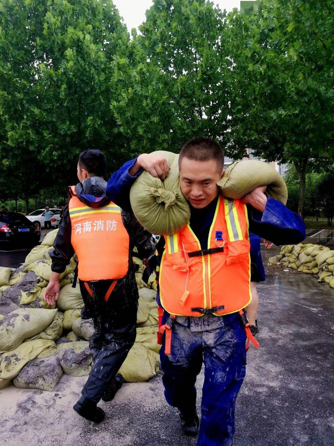 组织防汛围挡工作时,两名从此路过的年轻人也加入进来,和消防员一起扛