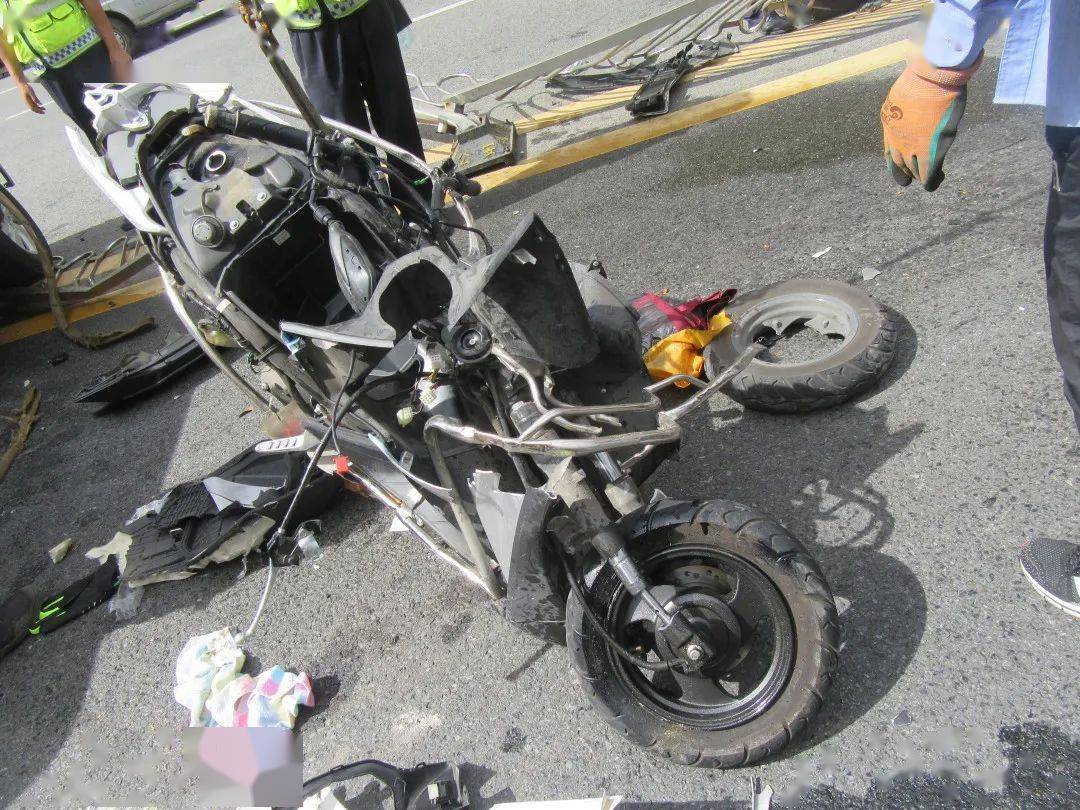 被撞的摩托车几乎散架,肇事的黑色小轿车横跨在道路中心,车头压着