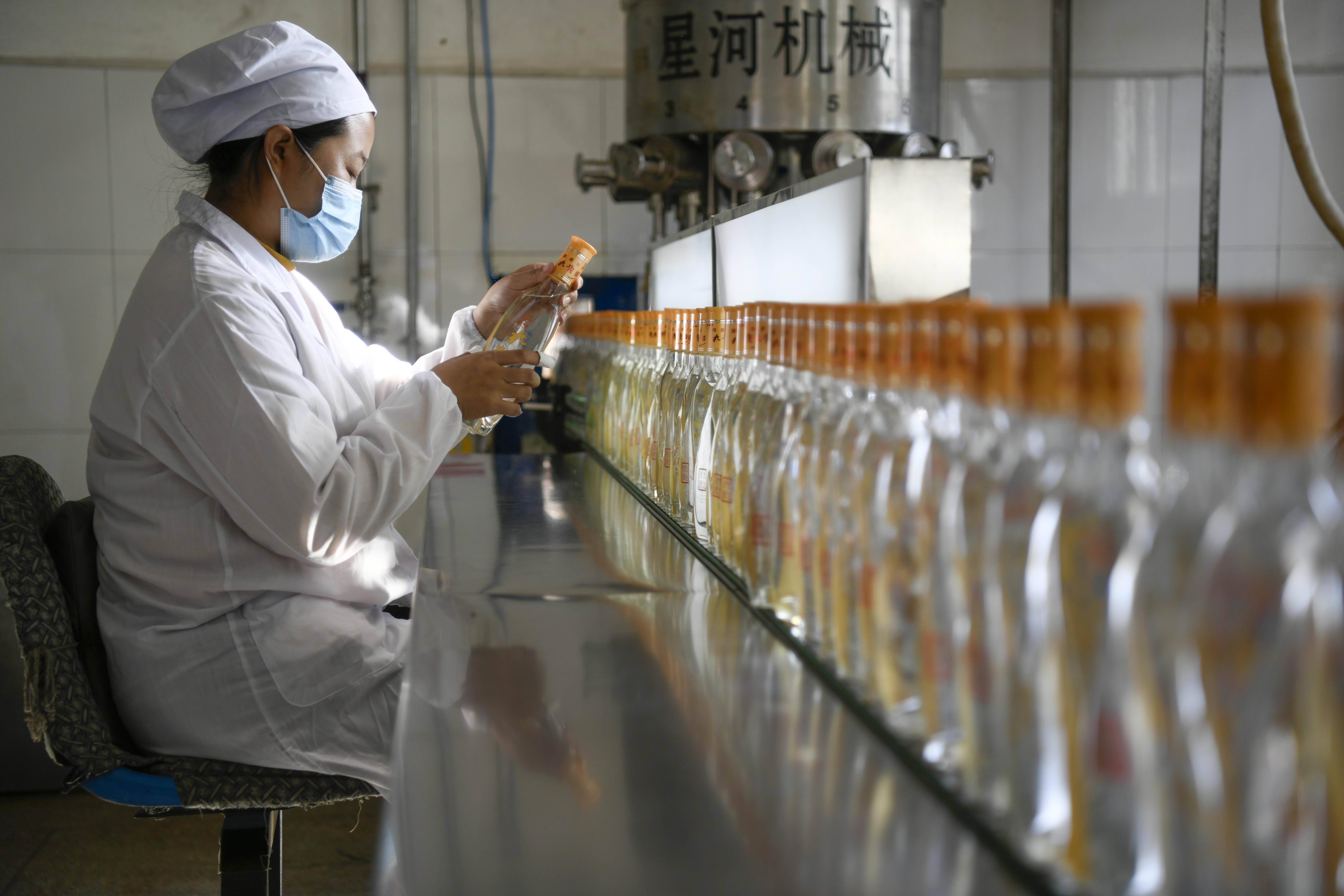 10月23日,在丰宁县一家酿酒企业,工人在酿酒车间查看酒的品质