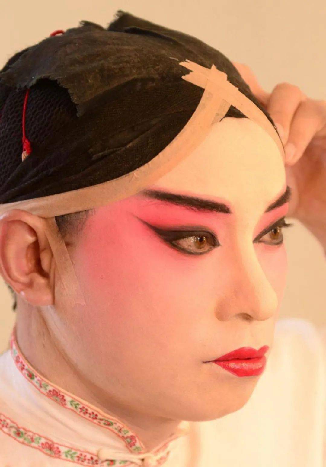 演员在化完妆后,会将眼角和前额使劲向上勒紧后扎起来.