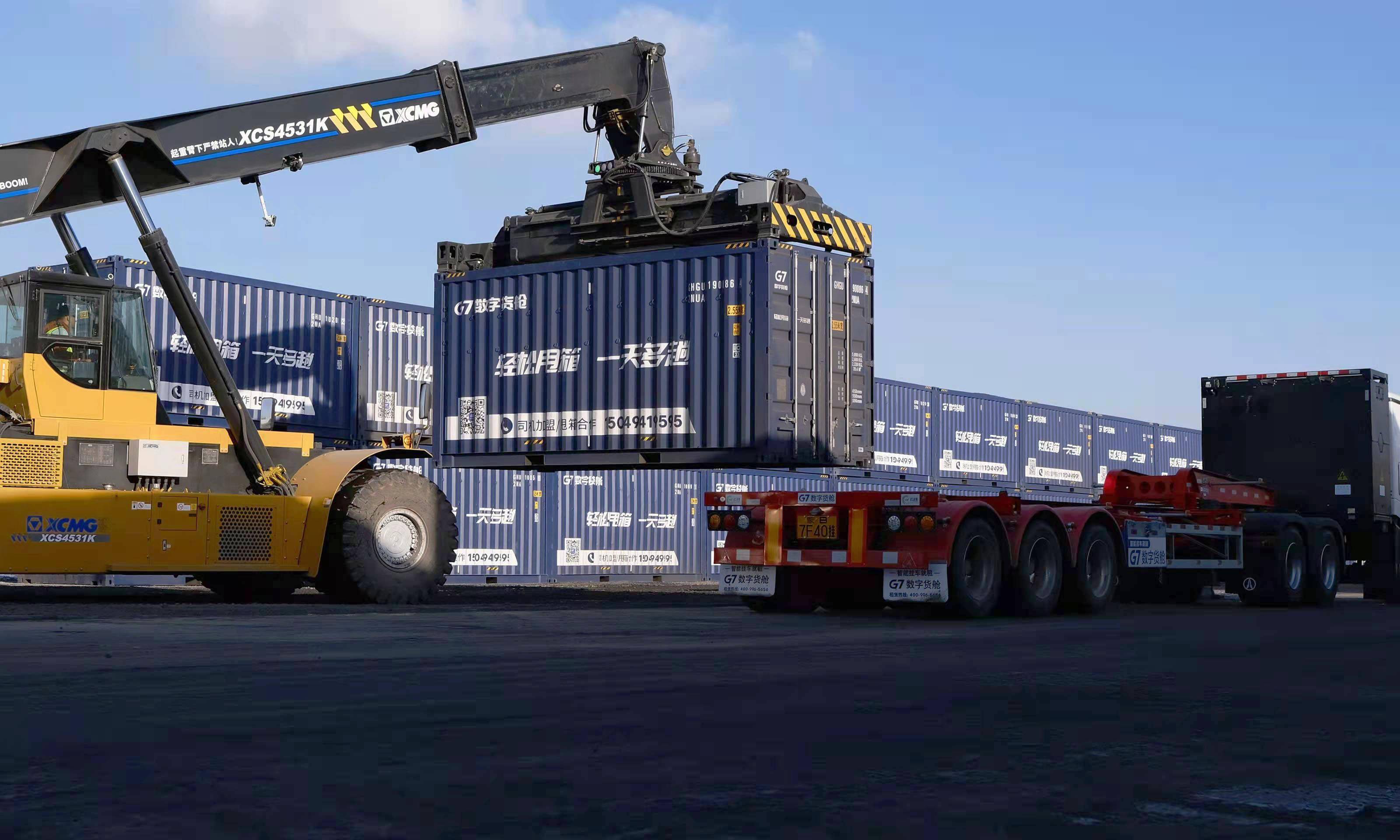 吊车从卡车上卸集装箱(2021年12月19日摄)