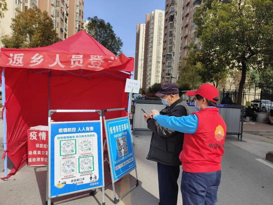 协助防疫人员对进入小区的居民进行测量体温