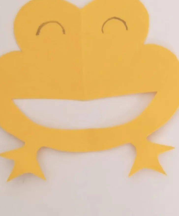3.用剪刀沿着画好的痕迹剪出来.2.用笔沿着中间的折痕画半个小青蛙.1.