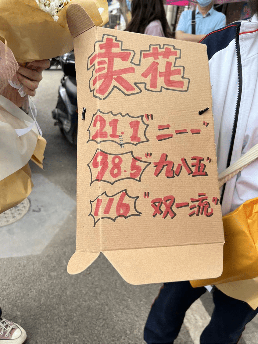 几名高二学生正在卖花,花束以向日葵为主,辅以满天星.