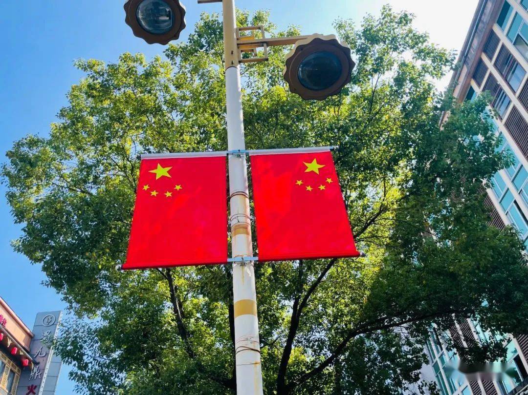 国旗的红色尤为鲜艳在街道绿树与蓝天白云的衬托下已经装点上崭新的