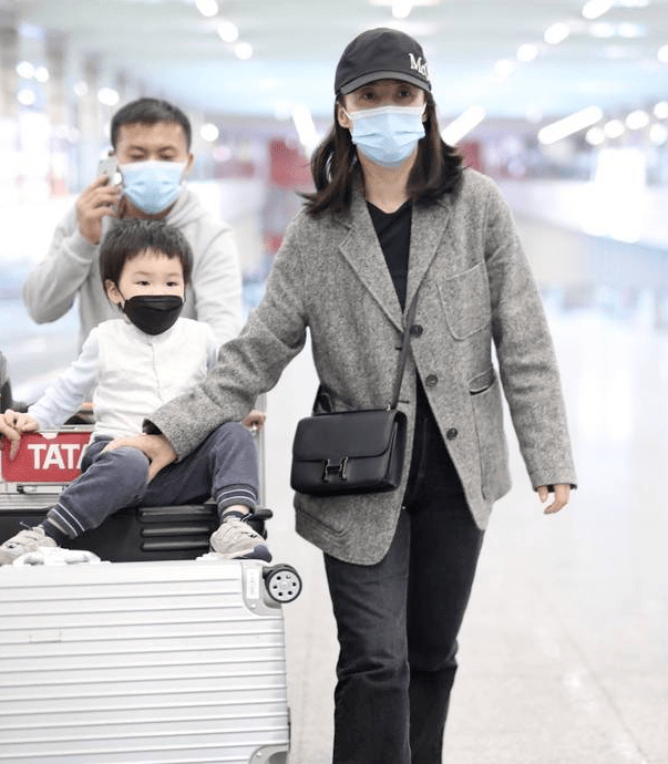 而蒋勤勤的小儿子锵锵头发漆黑茂密,衣着白色马甲灵巧坐在行李架上