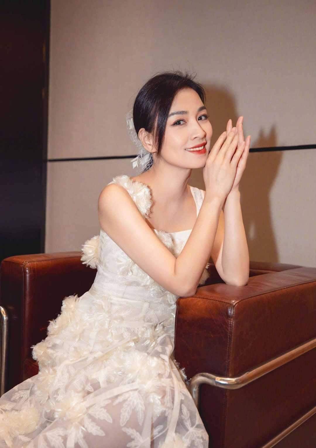 张庭夫妇又高调秀恩爱,穿白色吊带连衣裙配低马尾,哪像50岁_感觉_的